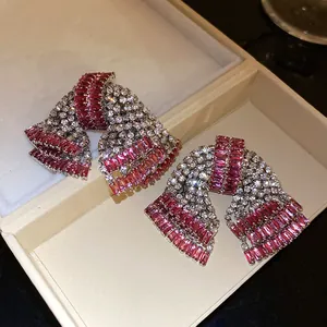 Detailed macro view of sparkling pink and white zircon bow-knot earrings in a gift box
