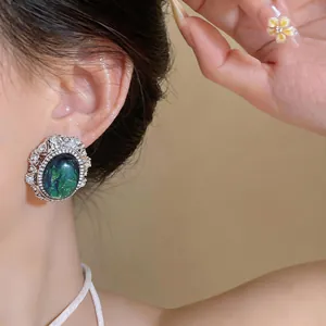 Macro detail shot of vintage oval resin earring with rhinestones worn on model ear