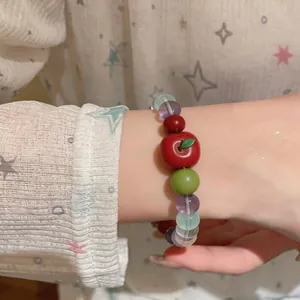 Close-up view of a sweet resin apple beaded bracelet with colorful stones on a female wrist