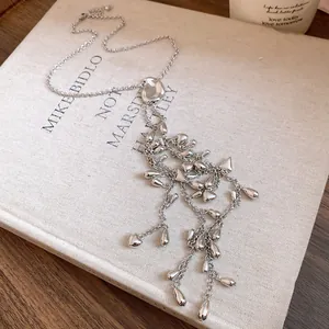 Vue détaillée du collier à pampilles argenté avec breloques gouttes d'eau sur un livre
