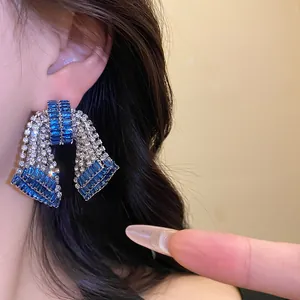 Macro detail shot of sparkling blue and silver zircon bow stud earrings on model