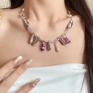 Vue détaillée d'un collier à pompons avec pendentifs argentés, perles violettes.