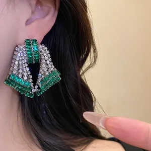 Macro detail view of luxury exaggerated emerald green zircon earrings worn on an ear