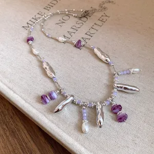 Vue détaillée d'un collier minimaliste avec des perles mauves et pendentifs argentés