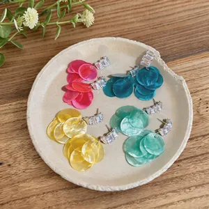 Detailed view of colorful shell tassel earrings with zircon studs on a decorative plate.
