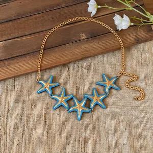 Detailed view of gold chain necklace featuring five blue enamel starfish pendants