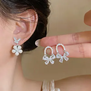 Detailed view of elegant pearl flower and zirconia butterfly bow earrings on ear.