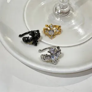 Detailed view of three French-style zircon cross iris flower ear cuffs in gold, silver, and black