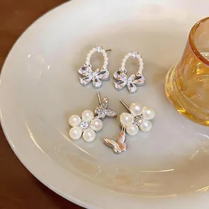 Close-up of elegant French style pearl earrings with zircon butterfly design on a white plate