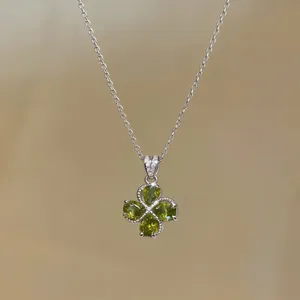 Detail shot of a vintage-style silver necklace featuring a green zircon flower pendant