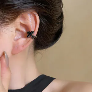 Close-up of elegant black fleur-de-lis cross ear cuff with zircon for non-pierced ears