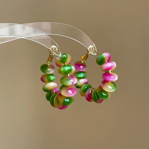 Detailed view of handmade hoop earrings with glossy gradient green and pink resin beads