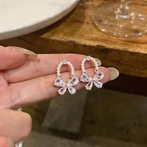 Close-up detail of elegant zircon bow earrings featuring a delicate pearl ring design