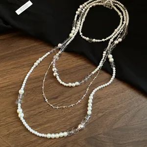 Detailed close-up of a four-piece layered pearl necklace set with silver cross charms
