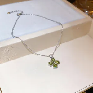 Macro detail of silver necklace featuring a green heart zircon flower pendant in a box