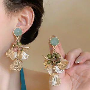 Gros plan détaillé de boucles d'oreilles vintage fleurs dorées avec pierre verte