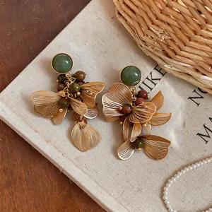 Vue macro détaillée de boucles d'oreilles fleurs dorées vintage avec perles vertes