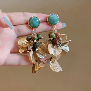 Gros plan de boucles d'oreilles fleurs vintage avec perles vertes et pétales d'or