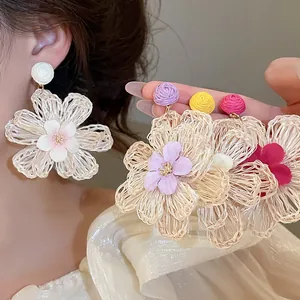 Detail view of handmade Bohemian raffia flower earrings in multiple summer colors