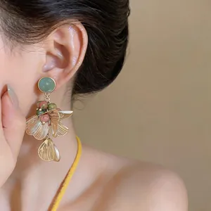 Gros plan de boucles d'oreilles pendantes fleurs dorées vintage sur un modèle