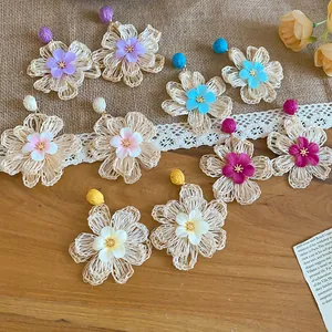 Detailed view of handmade Bohemian raffia flower earrings in multiple summer colors