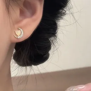 Detail view showing a dainty crescent moon and heart opal stud earring worn on ear