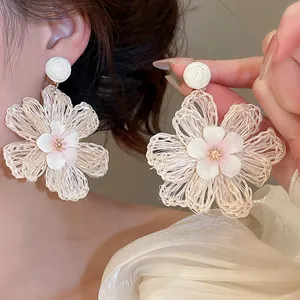 Close-up view of bohemian woven raffia flower earrings being worn and displayed