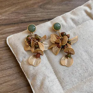 Gros plan détaillé de boucles d'oreilles pendantes fleurs dorées vintage avec perles