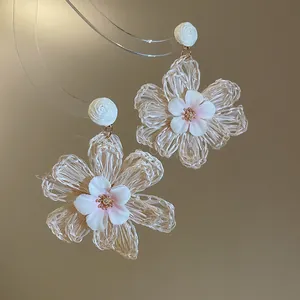 Close-up of bohemian raffia flower earrings with delicate pink and white floral details