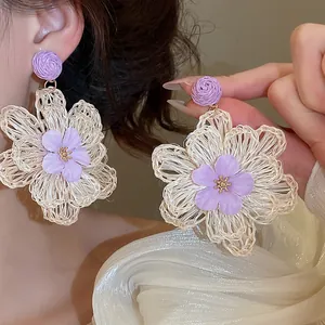 Macro detail view of Bohemian style raffia flower earrings with purple fabric petals