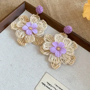 Detailed view of Bohemian raffia flower earrings with purple fabric accents