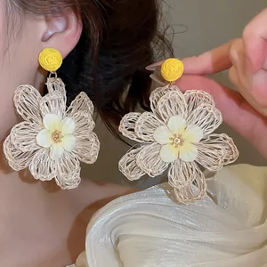 Close-up showing the intricate woven texture of these Bohemian style raffia flower earrings