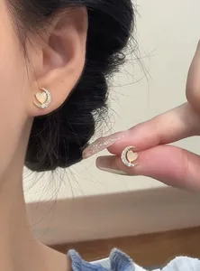 Detail view of dainty moon and heart stud earrings with opal and cubic zirconia