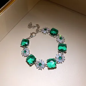Detailaufnahme eines luxuriösen Armbands mit grünen Zirkonia und funkelnden Blumenmustern