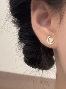 Close-up of zircon-encrusted moon stud earring with a cat's eye stone heart detail