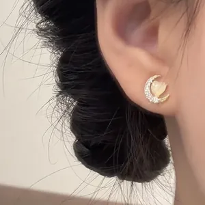 Detailed view of an elegant moon cat's eye heart stud earring worn on a model's ear.