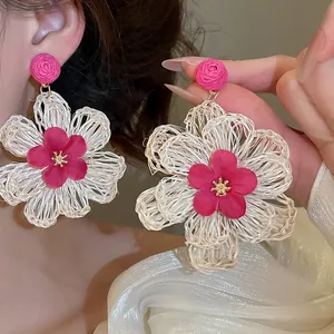 Detailed view of bohemian raffia flower earrings with vibrant pink floral centers