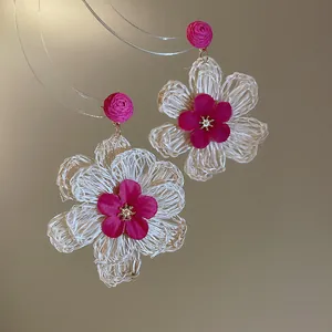 Close-up shot of Bohemian raffia flower earrings with vibrant magenta petal details.