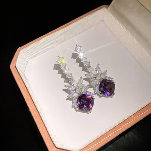 Detail of purple cushion-cut gemstone earrings with leaf-shaped zircon accents in a box