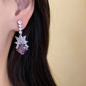 Close-up of elegant rhombus zircon drop earrings featuring a vibrant purple stone.