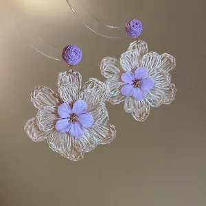 Macro view of Bohemian raffia flower earrings featuring delicate purple flower centers.