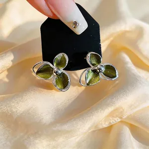 Elegant silver stud earrings with green enamel flower design and glossy finish