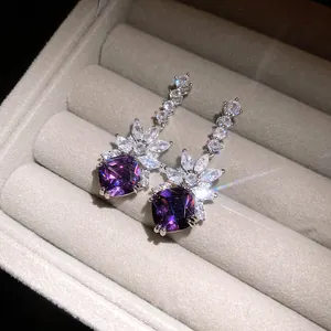 Detailed close-up view of elegant purple zircon dangle earrings in a plush jewelry box
