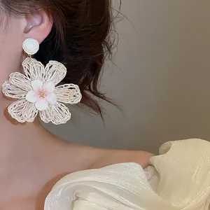 Close-up detail of bohemian white raffia flower earring with pink center