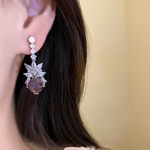 Detailed shot of vintage silver earrings with a purple zircon pendant worn by a model.