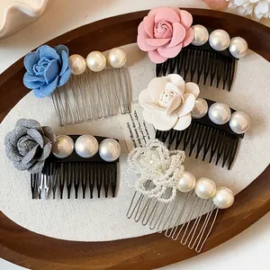 Selection of elegant French style fabric rose and faux pearl hair combs displayed in a wooden tray