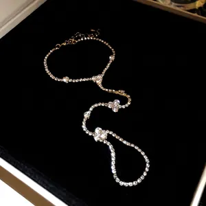 Minimalist golden hand harness with sparkling rhinestone ring and bracelet chain.