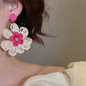 A detailed macro view showing the texture of a bohemian raffia flower earring on a model