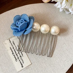 Detailed macro view of French style hair comb featuring a blue fabric flower and white pearls.
