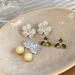 Assorted floral stud earrings set including daisy pearls and enamel camellia styles.